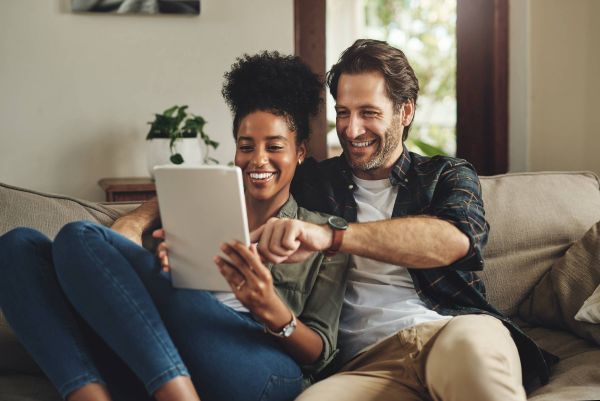 Couple sitting on couch looking at tablet